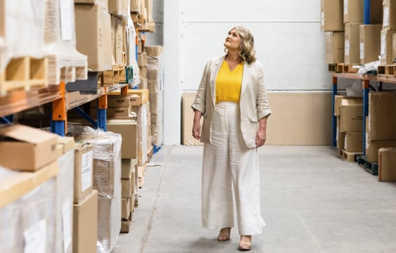 Woman in yellow top inspecting warehouse boxes